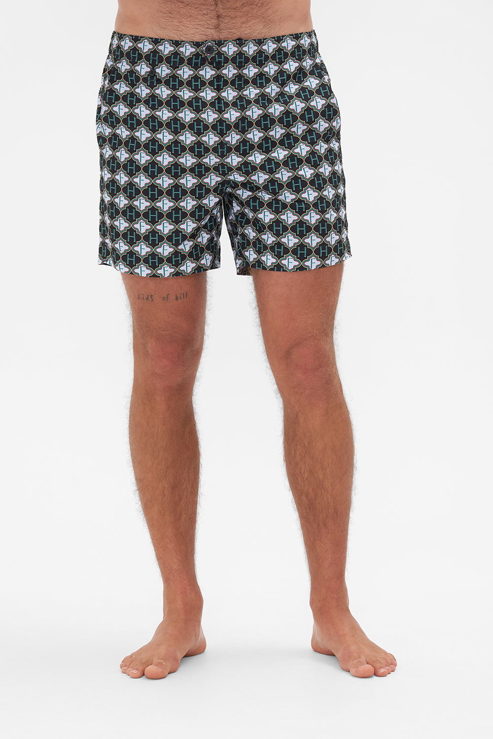 Crop view of model wearing Hotel Franks by CAMILLA mens monogram print boardshorts in Jealousy And Jewels print