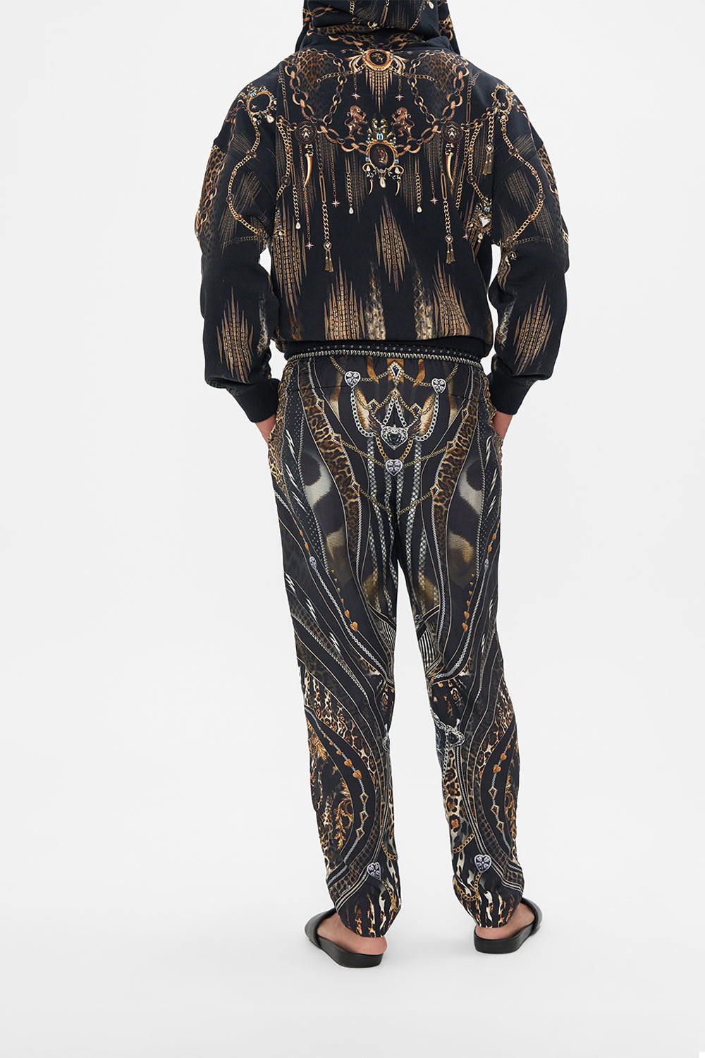 Back view of model wearing Hotel Franks by CAMILLA mens pants in Chaos In The Cosmos animal print 