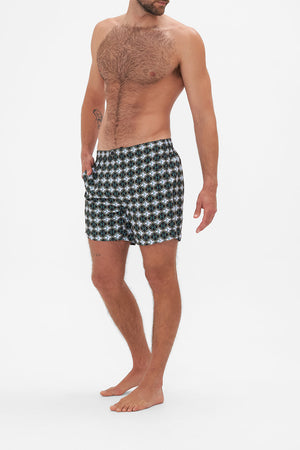 Side view of model wearing Hotel Franks by CAMILLA mens monogram print boardshorts in Jealousy And Jewels print