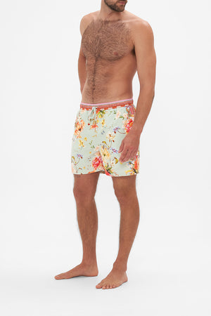 Side view of model wearing Hotel Franks by CAMILLA mens floral print boardshorts in Talk The Walk print