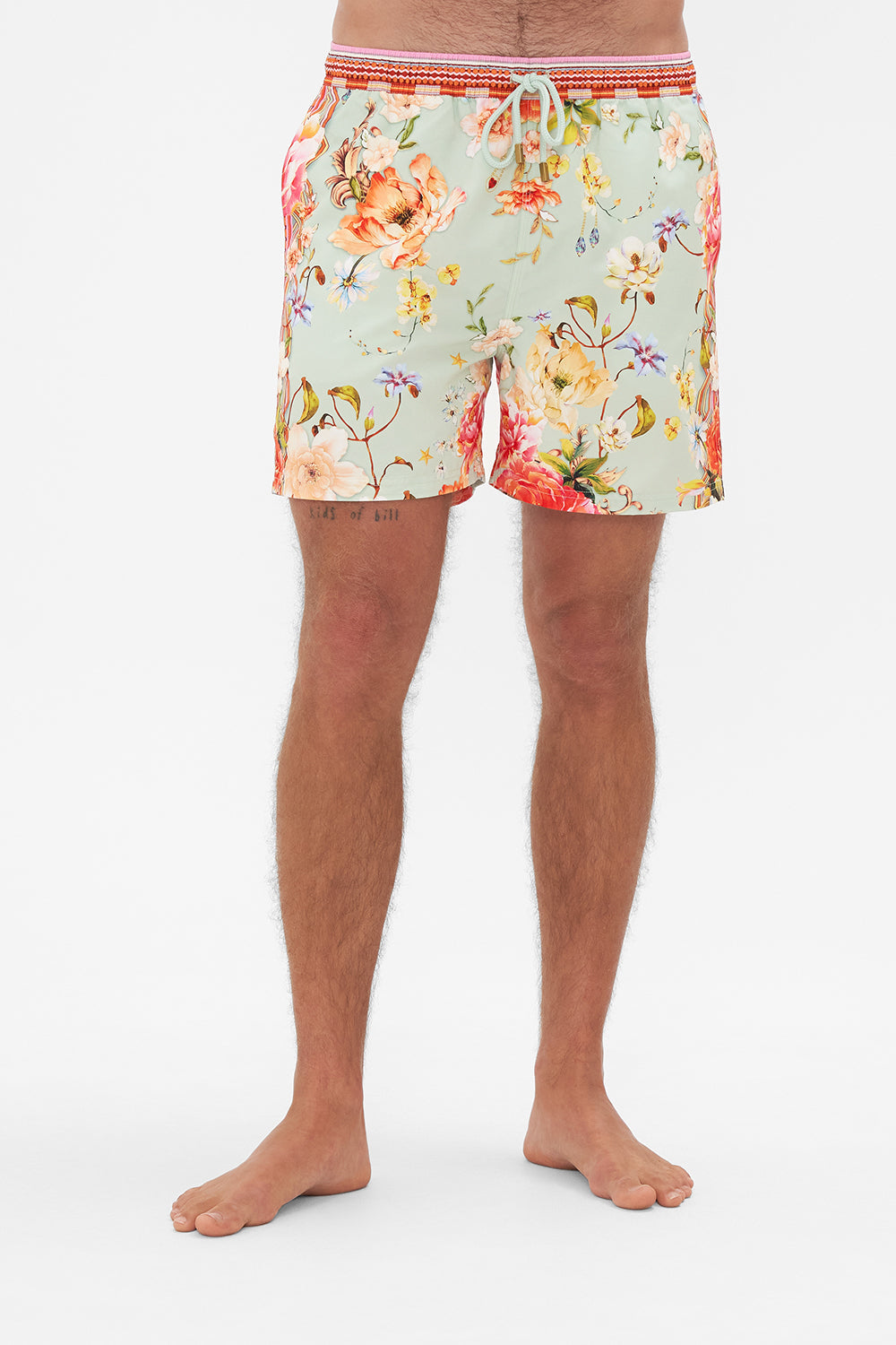 Crop view of model wearing Hotel Franks by CAMILLA mens floral print boardshorts in Talk The Walk print