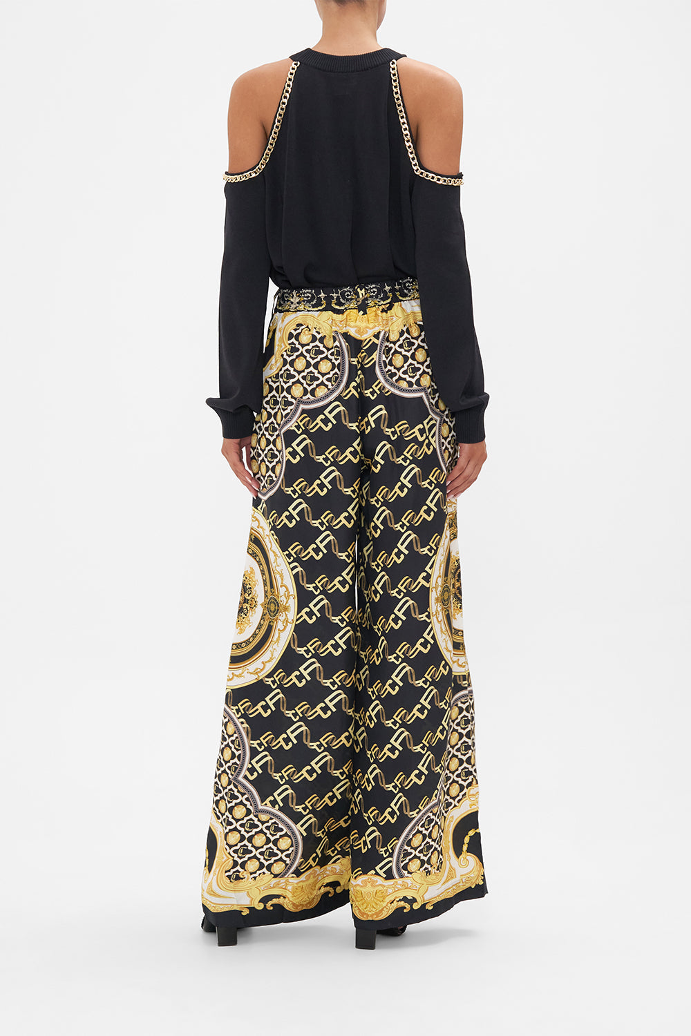 Back view of model wearing CAMILLA black silk pants in Tether Me Not print