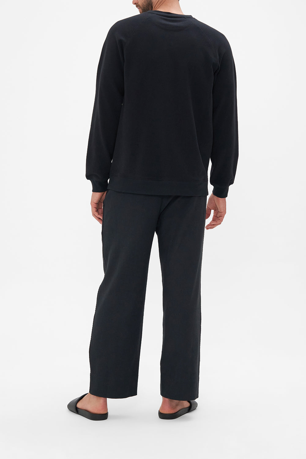 Back view of model wearing Hotel Franks by CAMILLA silk mens black knit jumper in Secret History floral print