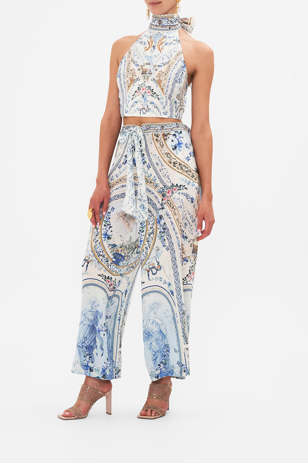 Crop view of model wearing CAMILLA blue silk pants in Season Of The Siren print 