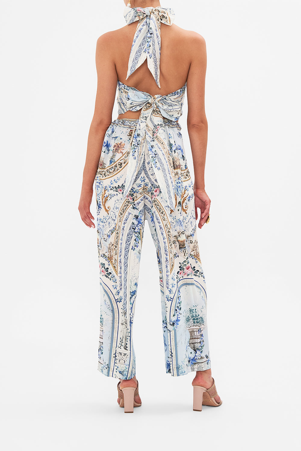Back view of model wearing CAMILLA blue silk pants in Season Of The Siren print 