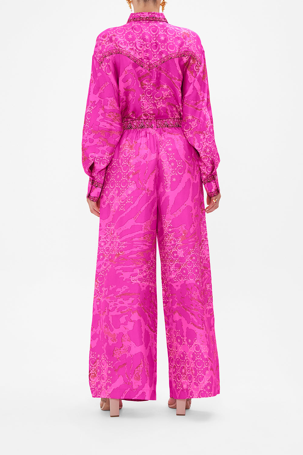 Back view of model wearing CAMILLA silk pants in neon Song Of Sacrifice print